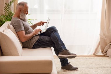 Dizüstü bilgisayar kullanan kıdemli adam.