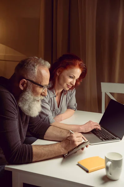 Пара среднего возраста, работающая на ноутбуке — стоковое фото