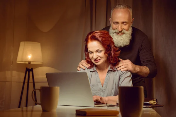 中间的中年的夫妇，看着笔记本电脑 — 图库照片