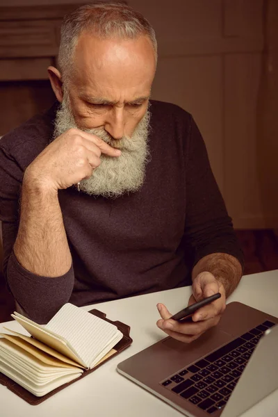 Hombre usando el teléfono inteligente en pose reflexiva — Foto de stock gratuita