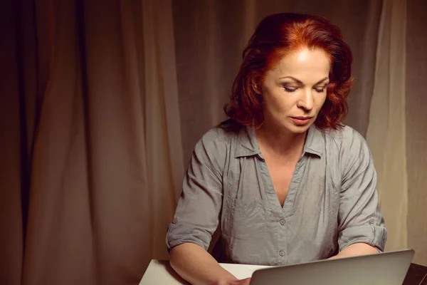 Pensive woman working on laptop at home Stock Image