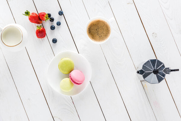 macarons with coffee and strawberries on wooden tabletop