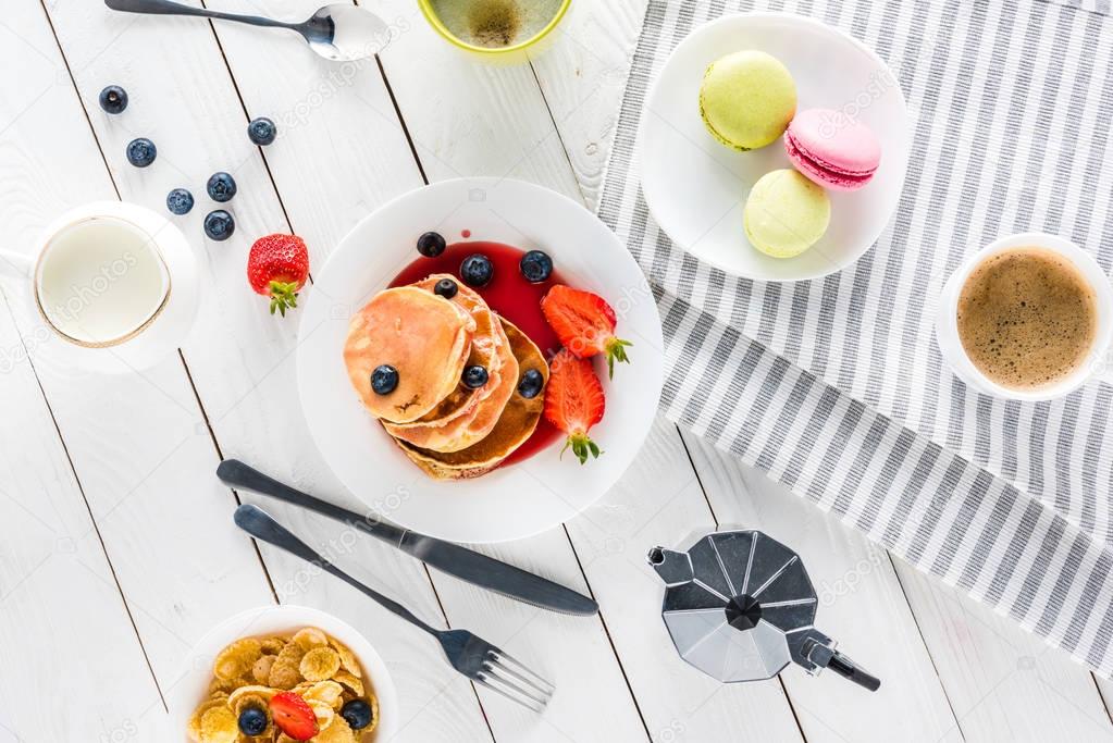 pancakes with macarons and coffee on wooden tabletop