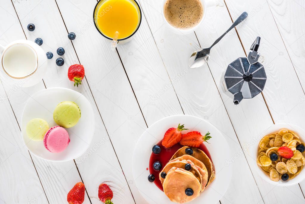 pancakes with macarons and coffee on wooden tabletop