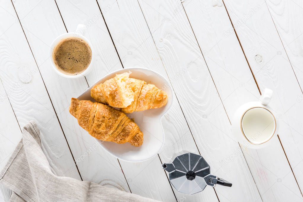croissants with coffee and milk on wooden tabletop