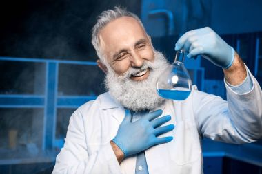 mature scientist holding flask with reagent