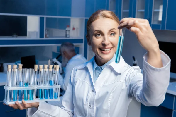 Хімік в лабораторному пальто тримає трубки — стокове фото