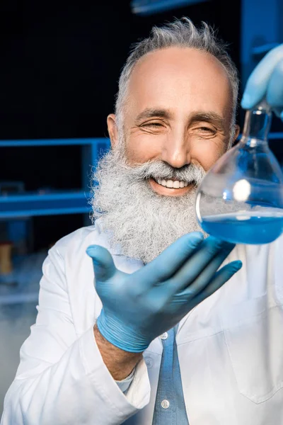 Científico de pelo gris sosteniendo matraz — Foto de stock gratis