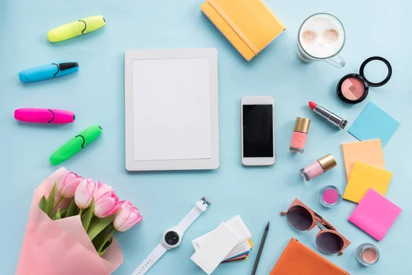 Tablet, diverse tilbehør og blomster på bordplade - Stock-foto