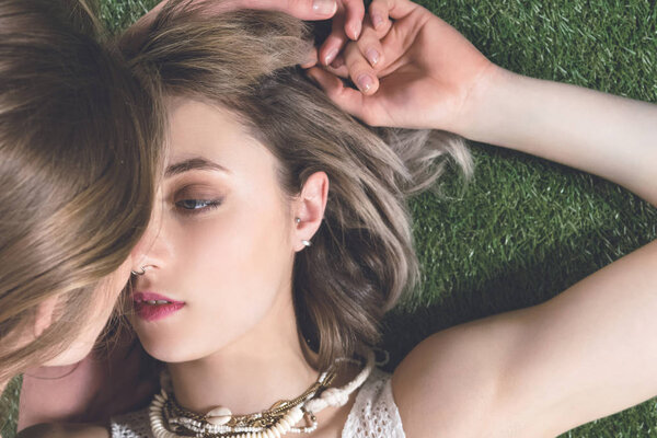 лесбийская пара целуется, лежа на траве
