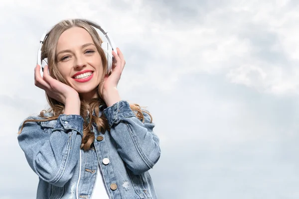 Mujer sonriente escuchando música en auriculares — Foto de Stock