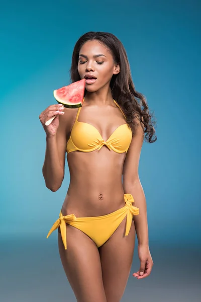 Ung kvinna i baddräkt som äter vattenmelon — Stockfoto