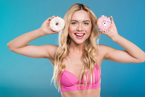 Mulher sorridente de maiô segurando donuts — Fotografia de Stock