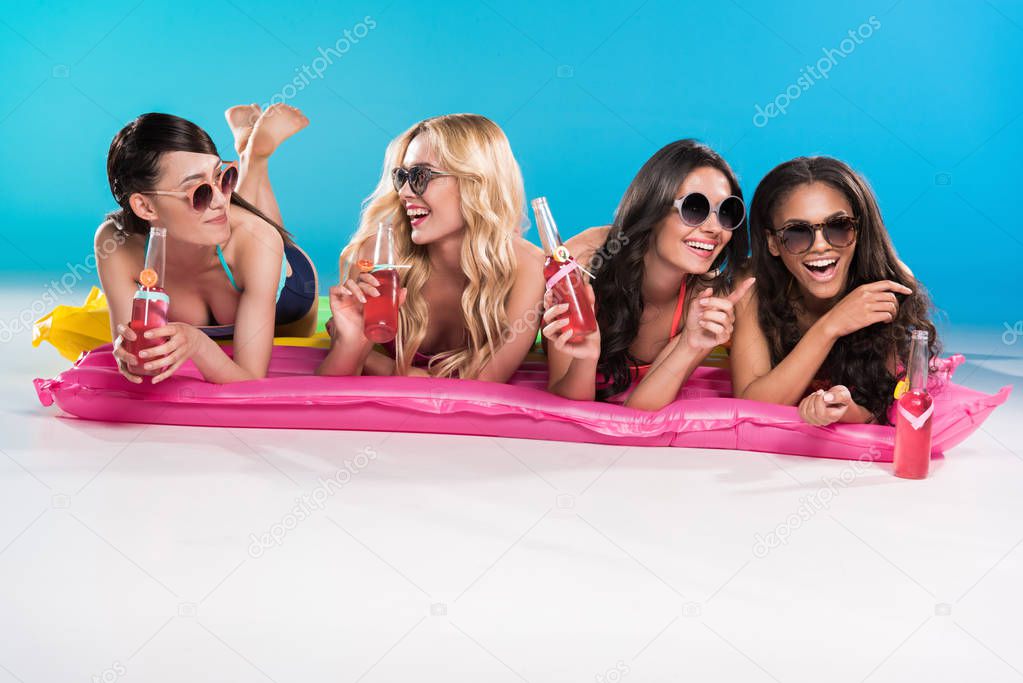 friends in sunglasses lying on swimming mattresses