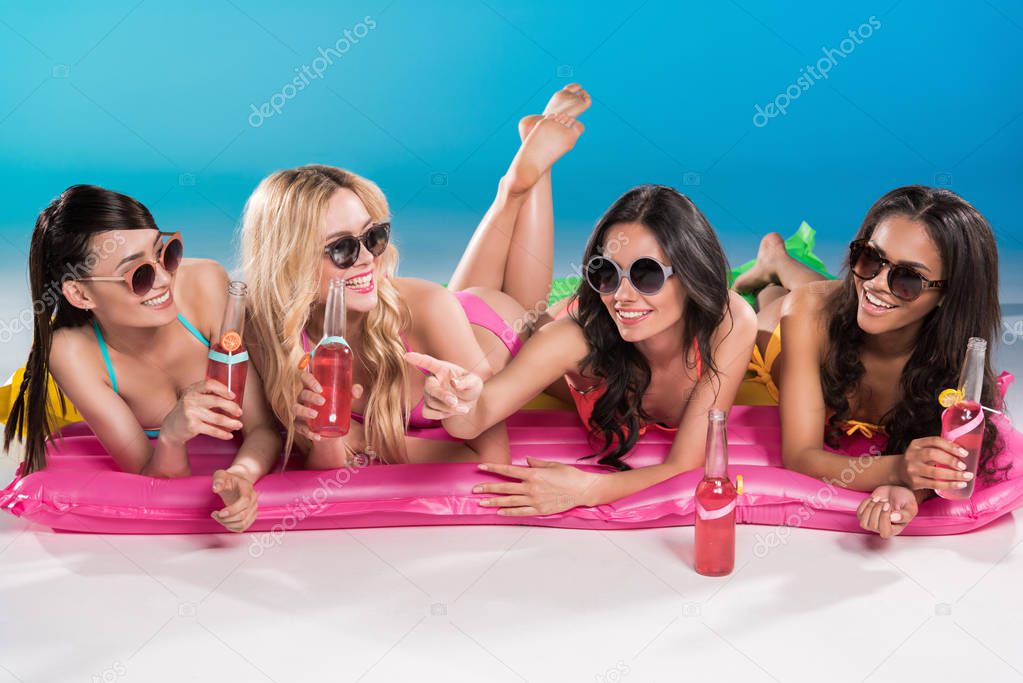 friends in sunglasses lying on swimming mattresses