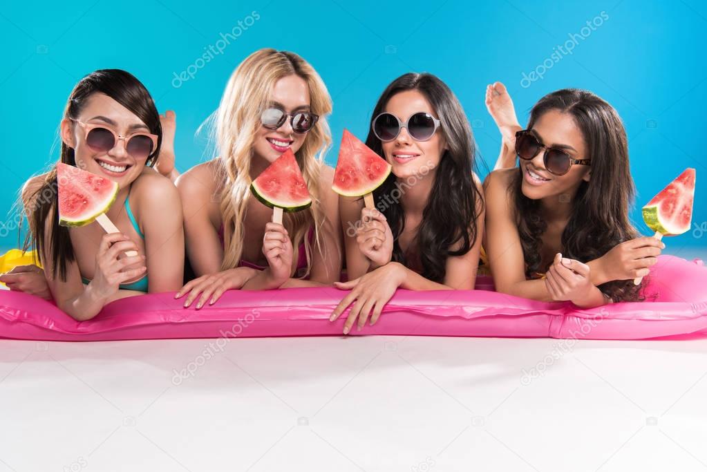 multiethnic girls lying on swimming mattress