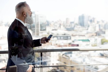 Balkonda Smartphone kullanarak iş adamı