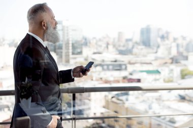 businessman using smartphone on balcony clipart