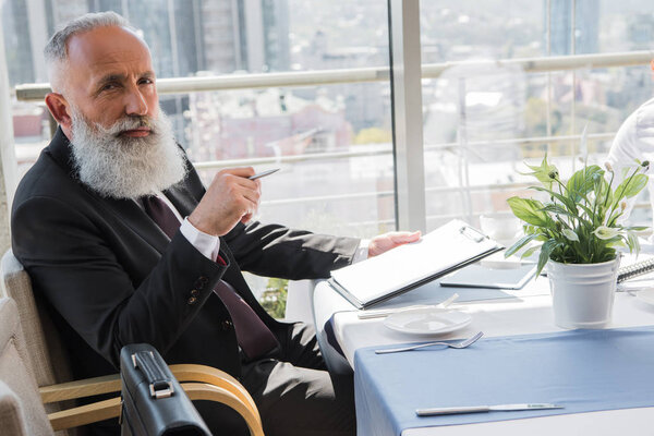 серьезный зрелый бизнесмен с буфером обмена
