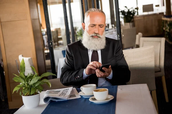 Бизнесмен использует смартфон в ресторане — стоковое фото