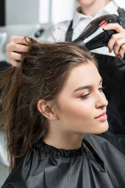 hairdresser drying hair of woman