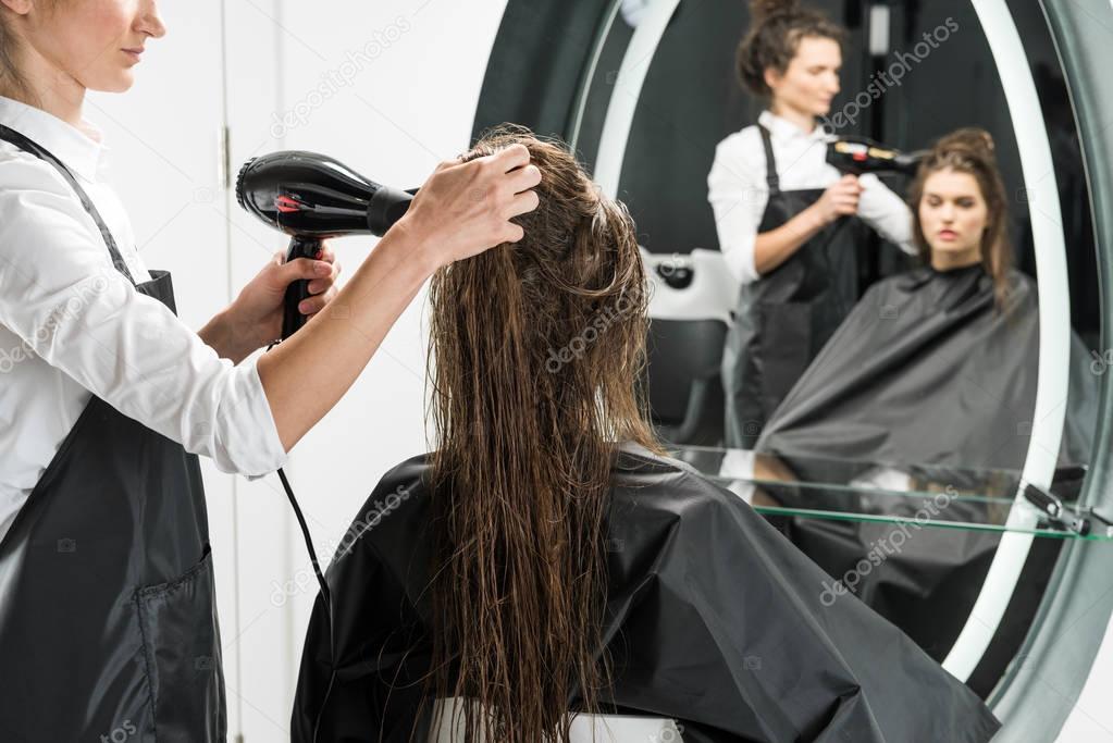 hairdresser drying hair of woman