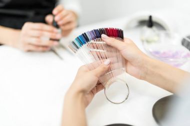 woman choosing nail polish color clipart
