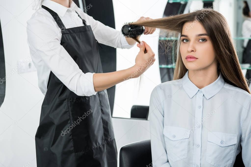 hairdresser brushing hair of woman