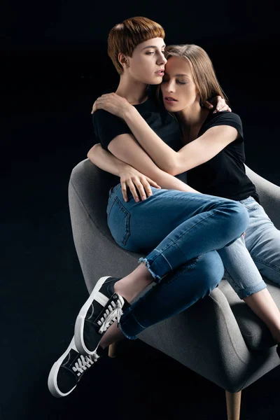 Lesbický pár objímat v křesle — Stock fotografie