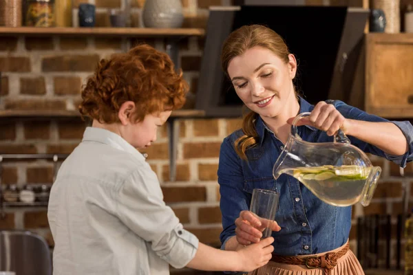 Mother pouring lemonade in glass — Stock Photo, Image