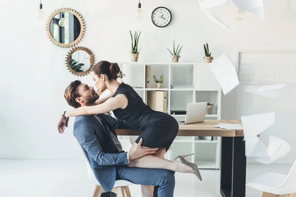 Женщина целует мужчину сидя на стуле — стоковое фото