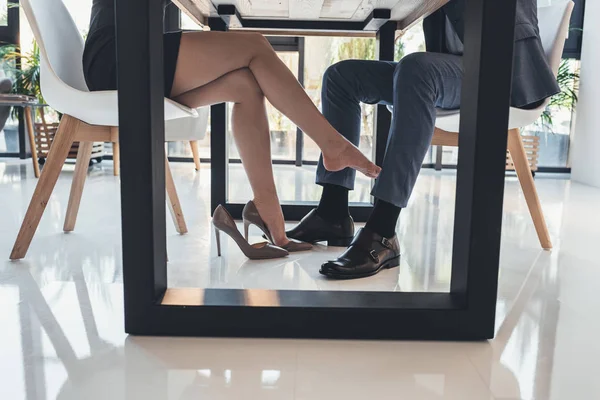 Woman flirting with man under table — Stock Photo, Image