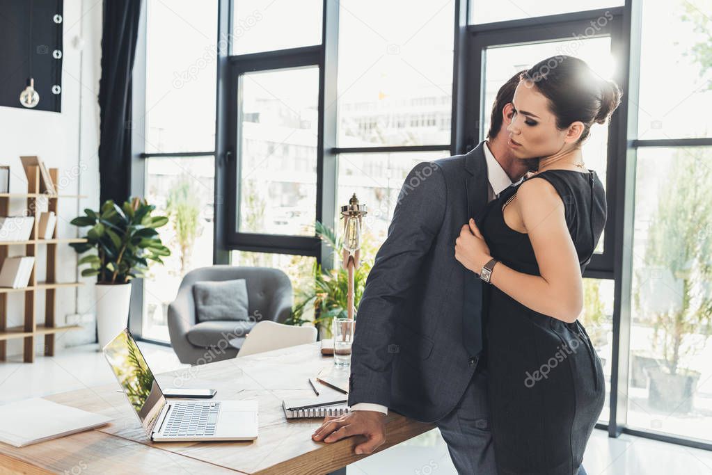 Man kissing woman on neck in office