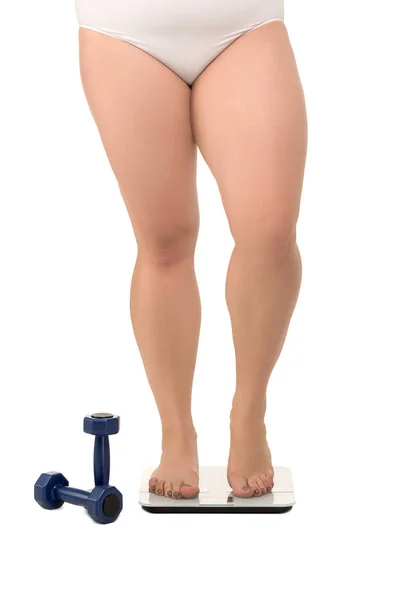 Fat woman on scales near dumbbells — Stock Photo, Image