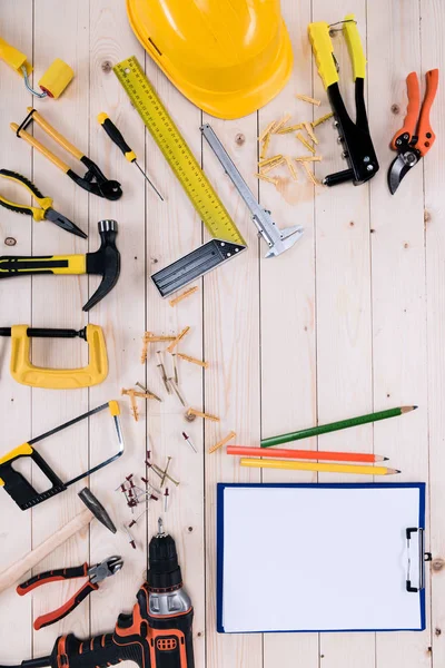 Draufsicht auf verschiedene Werkzeuge mit Klemmbrett auf Holztischplatte mit Kopierraum — Stockfoto