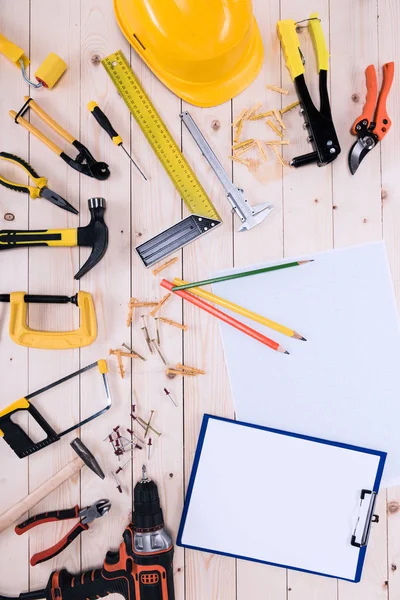 Top view of different tools with clipboard and blueprint on wooden tabletop — Stock Photo