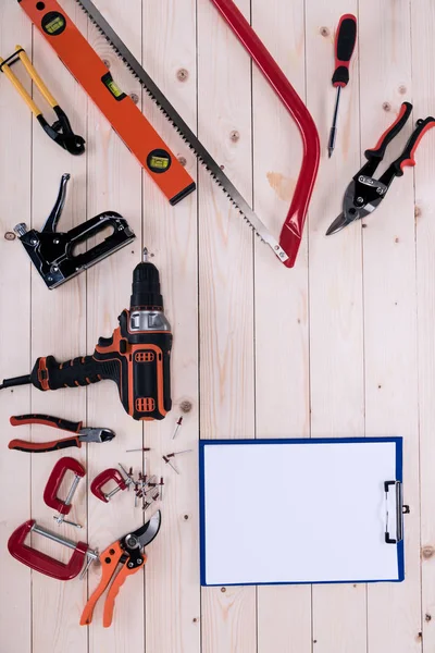 Vue de dessus de différents outils avec presse-papiers sur table en bois avec espace de copie — Photo de stock