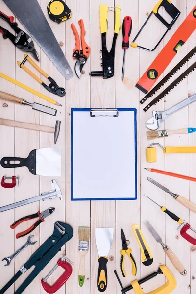 Draufsicht auf verschiedene Werkzeuge mit Klemmbrett auf Holztischplatte — Stockfoto