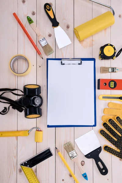 Top view of different tools with clipboard on wooden tabletop — Stock Photo