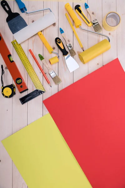 Vista superior do conjunto de ferramentas de construção e papel colorido na mesa de madeira — Fotografia de Stock