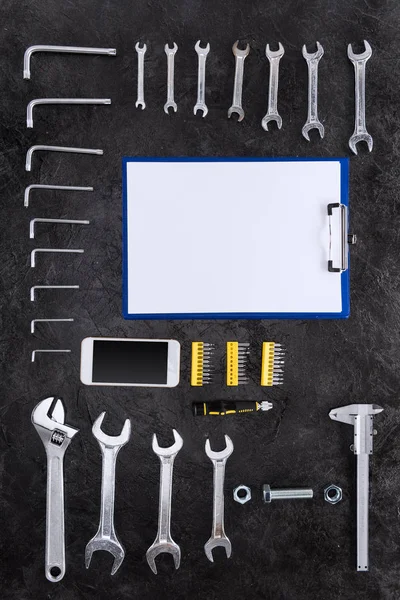 Vue du dessus de l'ensemble des outils de construction, smartphone et presse-papiers vierges — Photo de stock