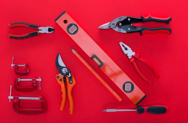 Вид зверху на різні робочі інструменти та олівець на червоному — стокове фото