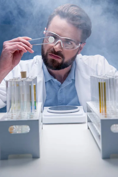 Chemist in goggles with reagents — Stock Photo