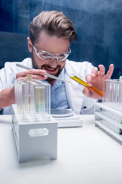 Chemist in goggles with reagents — Stock Photo