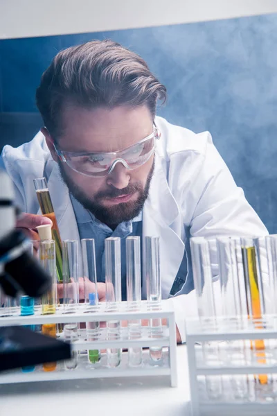 Chemist in goggles with reagents — Stock Photo