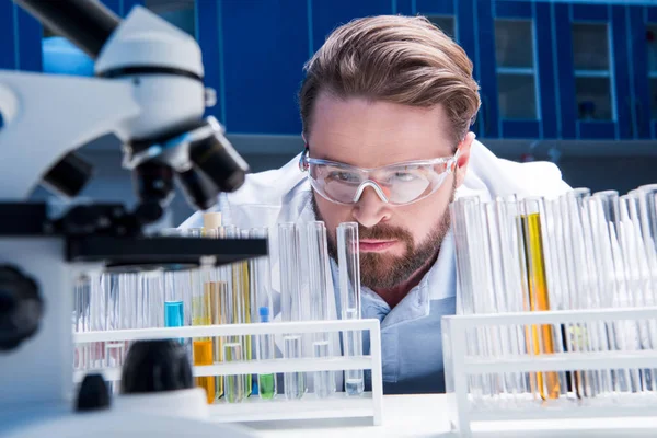 Chemist in goggles with reagents — Stock Photo