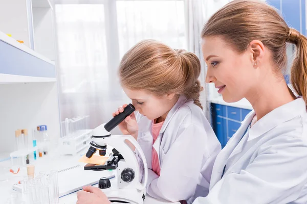 Profesor y estudiante trabajando con microscopio - foto de stock