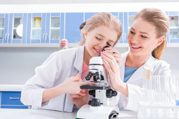 Teacher and student working with microscope — Stock Photo