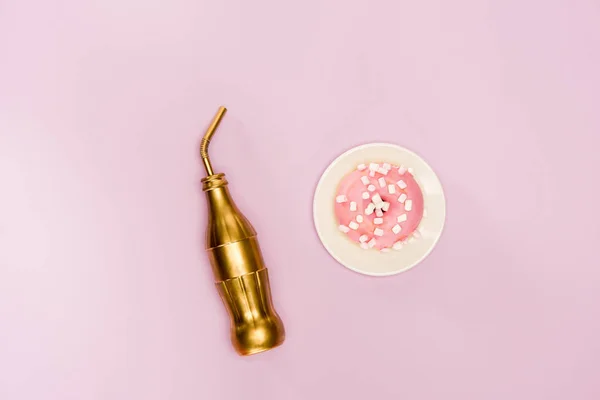 Donut in pink icing and golden bottle — Stock Photo