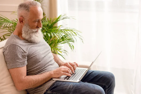 Homme âgé utilisant un ordinateur portable — Photo de stock